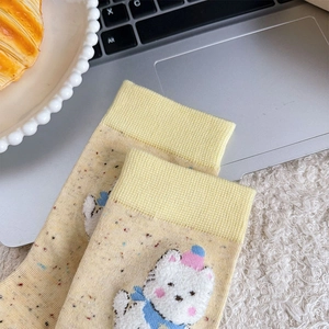 Détail d'une chaussette en coton jaune clair avec broderie ours et bordure côtelée