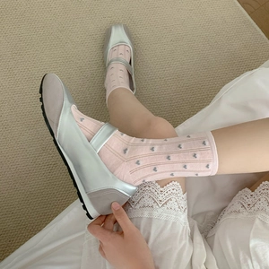 Close-up of pink heart pattern socks with silver Mary Jane shoes on a textured rug