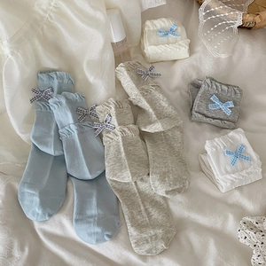 Detail view of cotton socks with ruffled edges and plaid bows in diverse pastel colors
