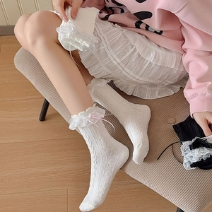 Close-up of white Lolita lace socks with pink ribbon bows and hollow knit pattern