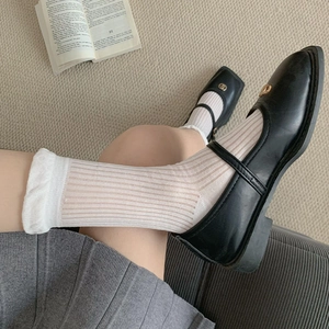 Detail of white semi-transparent striped mid-calf socks with wavy edges and Mary Jane shoes