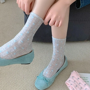 Detail of grey crew socks with blue hearts and pink stripes worn with suede bow flats
