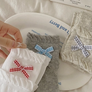 Detail of knit socks with double-layer ruffle edges and checkered ribbon bow accents