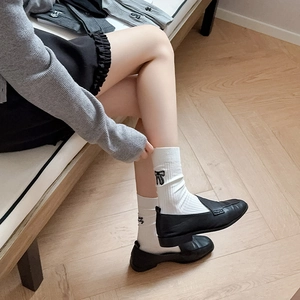 Close-up of ballet style white socks with black bow embroidery and letter detailing