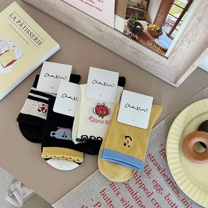 Detailed set of four cotton socks with cute cartoon embroidery on a wooden table
