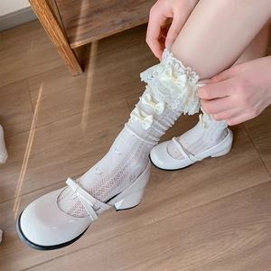 Close-up of cream white lace knee high socks with ribbon bows and heart cut-outs