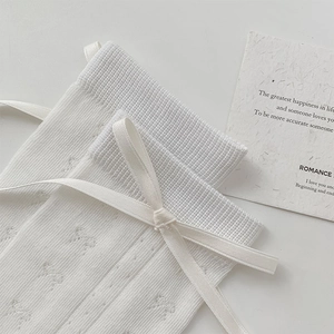 Détail de chaussettes blanches en maille avec motifs ajourés et nœuds en ruban de soie
