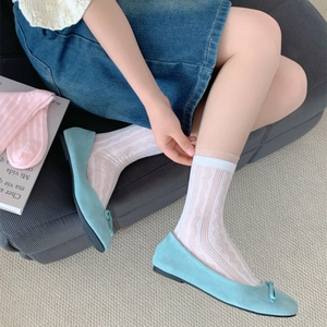 Détail de chaussettes en dentelle blanche ajourée avec ballerines bleues à nœud