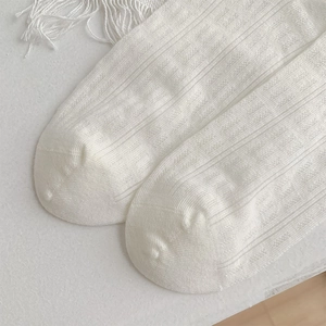 Détail de chaussettes blanches style ballet montrant la texture côtelée et la couture