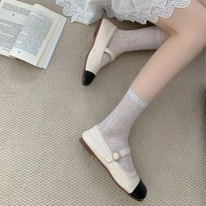 Gros plan sur des babies rétro crème à bout noir verni avec des chaussettes en dentelle