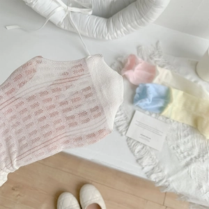 Détail de la texture en maille respirante et bord volanté sur chaussettes pastel