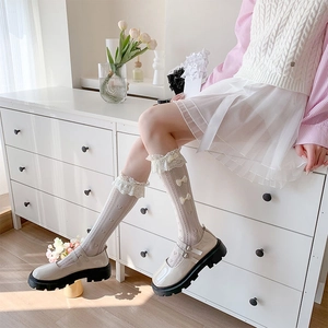 Detail of white lace hollow socks with bow accents paired with platform Mary Janes