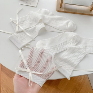 Vue détaillée de chaussettes résille blanches avec nœud en ruban et motif cœur