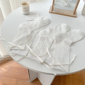 Gros plan de chaussettes blanches en maille avec rubans en soie et motifs cœurs