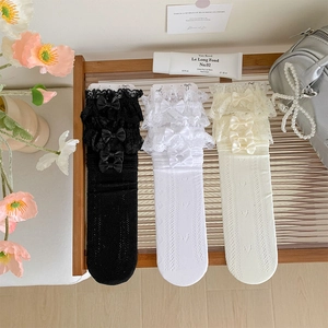 Detailed view of lace trim knee high socks with ribbon bows and heart hollow patterns