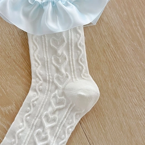 Détail macro de chaussettes en maille blanche avec motif cœur et bordure en dentelle