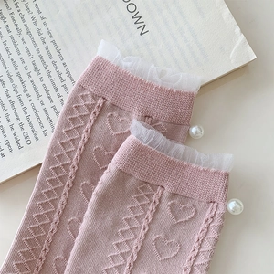 Close-up of pink socks with white lace trim, pearl accents and heart knit patterns