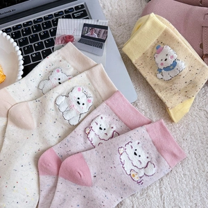 Détail de chaussettes à pois avec de mignons écussons d'ours en peluche 3D aux couleurs pastel