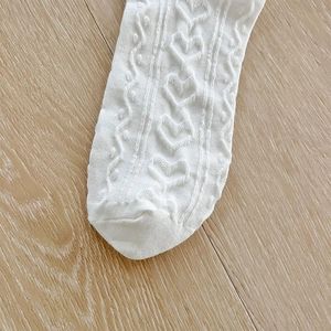 Détail de chaussettes Lolita blanches avec motifs de cœurs évidés et textures de tricotage