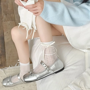 Gros plan de chaussures Mary Jane argentées à nœuds et chaussettes en résille blanche
