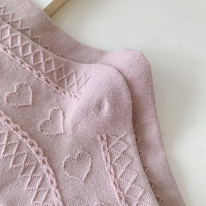 Detail of pink knitted socks featuring heart-shaped hollow patterns and breathable texture