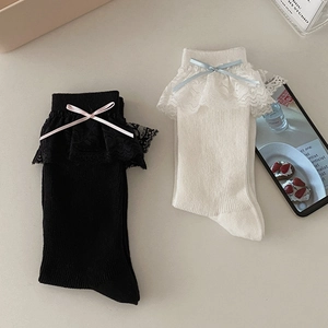 Détail de chaussettes en maille avec bordure en dentelle et nœuds ruban en noir et blanc