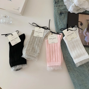 Détail de chaussettes en dentelle proposées en noir, gris, rose et blanc élégant