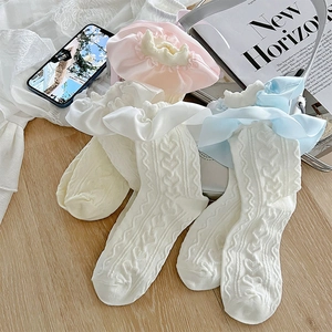 Détail de chaussettes en maille torsadée cœur avec bordure en satin à volants