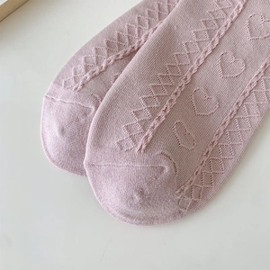 Close-up of pink heart-patterned lace socks with intricate hollow knit texture detail