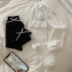 Détail de chaussettes Lolita avec dentelle et nœuds en ruban sur tissu texturé