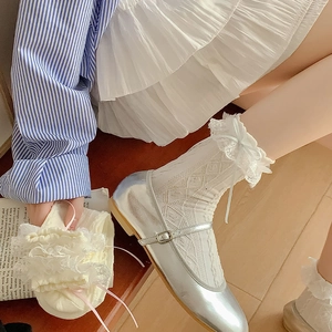 Detail of white lace mesh socks with blue ribbon bow and silver Mary Jane shoes