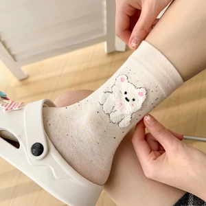 Vue détaillée de chaussettes en coton crème avec mouchetures et patch d'ours en peluche