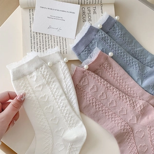 Detail of white lace trim socks featuring delicate pearls and heart-shaped hollow patterns