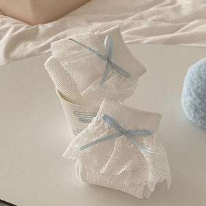 Détail de chaussettes lolita blanches avec bordure en dentelle et nœud en soie bleu