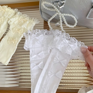 Close-up of white lace trim socks featuring hollow-out knit and satin ribbon bows