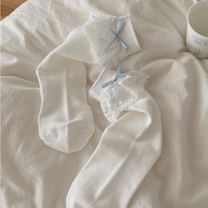 Détail de chaussettes en coton blanc avec dentelle délicate et nœuds en satin bleu