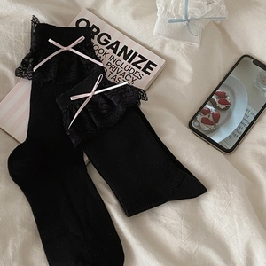 Détail de chaussettes Lolita noires avec dentelle délicate et nœuds en ruban rose
