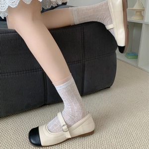 Gros plan sur des chaussettes en dentelle beige à motif ajouré avec des ballerines Mary Jane