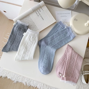 Detail of knit heart patterns, lace trim and pearl accents on white crew socks