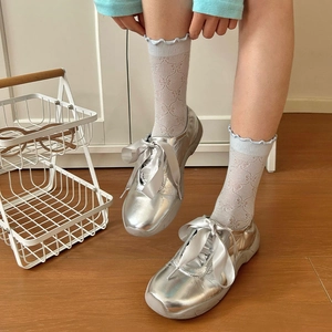 Dettaglio di calzini blu a fantasia con sneaker argentate e fiocco