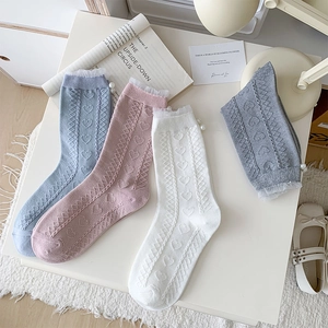 Close-up of white lace trim, pearl accents, and heart knit texture on cotton socks