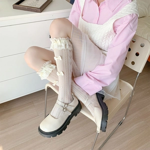 Detail of white lace trim socks with cream bows and beige platform Mary Jane shoes