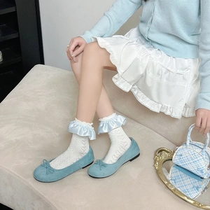 Détail de ballerines bleu clair avec chaussettes blanches à cœurs et volants en soie