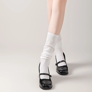 Detail of white ribbed knit slouch socks paired with black patent leather Mary Jane shoes