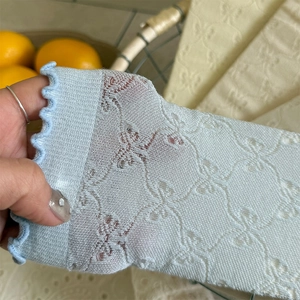 Dettaglio di calzini in mesh azzurro con motivi a fiocco e bordi elastici a balze