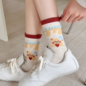 Detailed view of cute cotton socks featuring a cartoon bear and plush trim with white shoes