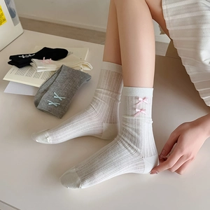 Close-up of vertical ribbed cotton socks featuring delicate side bow decorations
