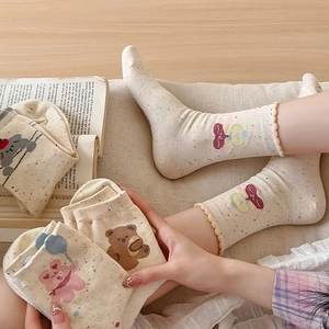 Close-up of cute bear and rabbit embroidery on speckled socks with wavy edges