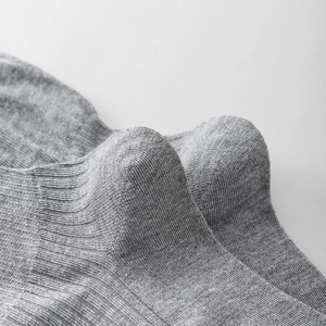 Close-up of gray fine-knit cotton socks showing reinforced heel and ribbed cuff texture