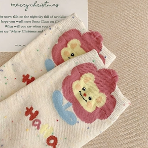 Detailed view of beige knit socks with colorful specks and cute lion cartoon embroidery